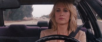Movie still from “Bridesmaids” (2011), directed by Paul Feig – A woman sitting in the driver's seat of a car driving down a street; Close Up shot, Over the shoulder angle