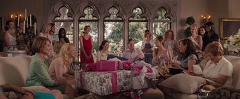 Movie still from “Bridesmaids” (2011), directed by Paul Feig – A group of people standing around a table with presents on it; Wide shot, Over the shoulder angle