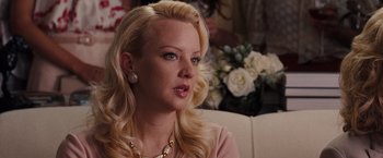 Movie still from “Bridesmaids” (2011), directed by Paul Feig – A woman sitting on a couch in front of flowers; Close Up shot, Over the shoulder angle