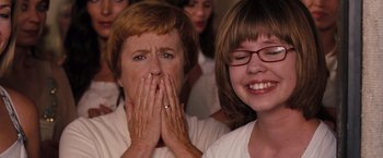 Movie still from “Bridesmaids” (2011), directed by Paul Feig – Two women sitting next to each other with one covering her mouth; Close Up shot, Over the shoulder angle