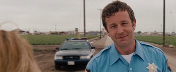 Movie still from “Bridesmaids” (2011), directed by Paul Feig – A police officer standing in front of a cop car; Close Up shot, Over the shoulder angle