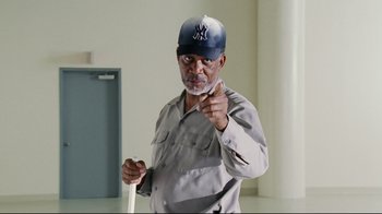 Movie still from “Bruce Almighty” (2003), directed by Tom Shadyac – An older man wearing a baseball cap and a uniform; Medium shot, Low angle