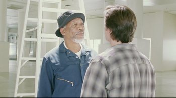 Movie still from “Bruce Almighty” (2003), directed by Tom Shadyac – A man wearing a hat talking to another man in front of a mirror; Medium shot, Over the shoulder angle