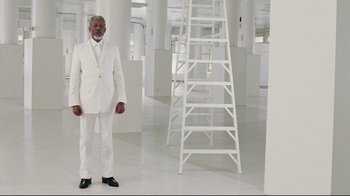 Movie still from “Bruce Almighty” (2003), directed by Tom Shadyac – A man in a white suit standing in front of a ladder; Wide shot, Low angle