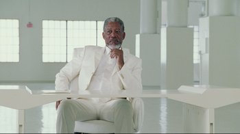 Movie still from “Bruce Almighty” (2003), directed by Tom Shadyac – An older man in a white suit sitting at a table; Medium shot, Over the shoulder angle