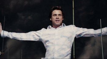 Movie still from “Bruce Almighty” (2003), directed by Tom Shadyac – A man in a white shirt is standing in front of a black background; Medium shot, Low angle