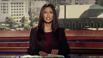 Movie still from “Bruce Almighty” (2003), directed by Tom Shadyac – A news anchor sitting at a desk in front of a tv; Close Up shot, Low angle