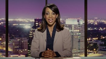 Movie still from “Bruce Almighty” (2003), directed by Tom Shadyac – A woman sitting at a desk in front of a city skyline; Medium shot, High angle
