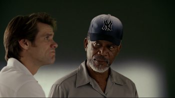 Movie still from “Bruce Almighty” (2003), directed by Tom Shadyac – A man wearing a yankees hat standing next to another man; Close Up shot, Over the shoulder angle