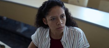Movie still from “Chambers” (2019), created by Leah Rachel – A woman with curly black hair wearing a striped shirt; Close Up shot, Over the shoulder angle
