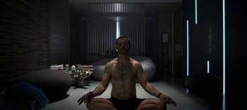 Movie still from “Chambers” (2019), created by Leah Rachel – A man is sitting in the middle of a meditative yoga pose; Medium shot, High angle