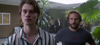 Movie still from “Chambers” (2019), created by Leah Rachel – Two men standing next to each other in front of a group of onlookers; Close Up shot, Over the shoulder angle