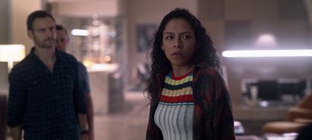Movie still from “Chambers” (2019), created by Leah Rachel – A woman with long curly black hair standing in a room; Medium shot, Over the shoulder angle
