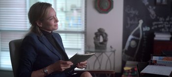 Movie still from “Chambers” (2019), created by Leah Rachel – A woman sitting in a chair holding an open book; Medium shot, Over the shoulder angle