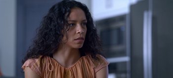 Movie still from “Chambers” (2019), created by Leah Rachel – A woman with long black curly hair wearing an orange top; Close Up shot, Over the shoulder angle