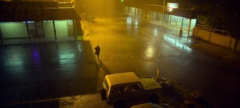 Movie still from “Chambers” (2019), created by Leah Rachel – A person walking on the sidewalk in the rain; Extreme Wide shot, High angle