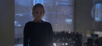 Movie still from “Chambers” (2019), created by Leah Rachel – A woman standing in front of a crowd of people in a room; Medium shot, Low angle