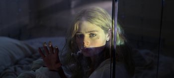 Movie still from “Chambers” (2019), created by Leah Rachel – A girl with long blonde hair looking out of a window; Close Up shot, Low angle