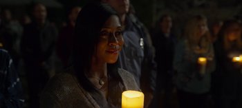 Movie still from “Chambers” (2019), created by Leah Rachel – A woman is holding a candle in a dark room; Close Up shot, Over the shoulder angle