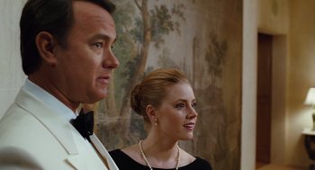 Movie still from “Charlie Wilson's War” (2007), directed by Mike Nichols – A man and a woman standing next to each other in front of a painting; Medium shot, Over the shoulder angle