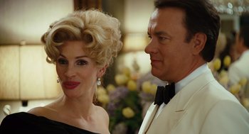 Movie still from “Charlie Wilson's War” (2007), directed by Mike Nichols – A man and a woman standing next to each other in front of flowers; Close Up shot, Over the shoulder angle