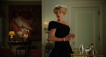 Movie still from “Charlie Wilson's War” (2007), directed by Mike Nichols – A woman in a black dress is holding a cigarette; Medium shot, Low angle