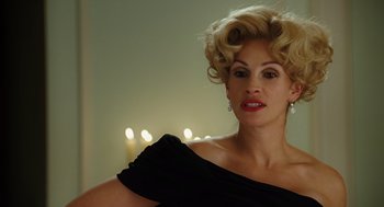 Movie still from “Charlie Wilson's War” (2007), directed by Mike Nichols – A woman in a black dress with a blonde hair style; Close Up shot, Over the shoulder angle