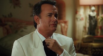 Movie still from “Charlie Wilson's War” (2007), directed by Mike Nichols – A man in a white suit adjusting his neck tie; Close Up shot, Over the shoulder angle