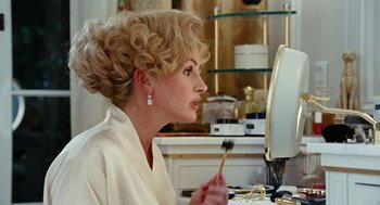 Movie still from “Charlie Wilson's War” (2007), directed by Mike Nichols – A woman in a white bathrobe brushes her teeth in front of a mirror; Close Up shot, Over the shoulder angle
