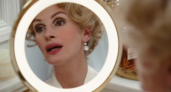 Movie still from “Charlie Wilson's War” (2007), directed by Mike Nichols – A woman looking into a mirror while wearing earrings; Close Up shot, Over the shoulder angle
