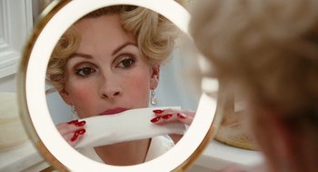 Movie still from “Charlie Wilson's War” (2007), directed by Mike Nichols – A woman is looking in the mirror while putting lipstick on her lips; Close Up shot, Low angle