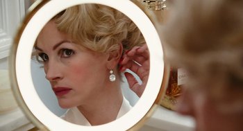 Movie still from “Charlie Wilson's War” (2007), directed by Mike Nichols – A woman putting on a pair of earrings in a mirror; Close Up shot, Over the shoulder angle