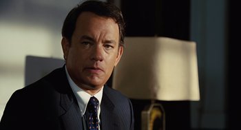 Movie still from “Charlie Wilson's War” (2007), directed by Mike Nichols – A man wearing a suit and tie in front of a lamp; Close Up shot, Over the shoulder angle