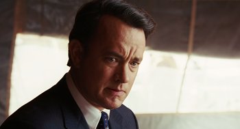 Movie still from “Charlie Wilson's War” (2007), directed by Mike Nichols – A man wearing a suit and tie looking at the camera; Close Up shot, Over the shoulder angle