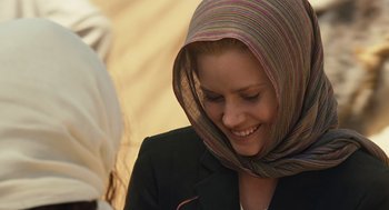 Movie still from “Charlie Wilson's War” (2007), directed by Mike Nichols – A woman wearing a headscarf smiling for the camera; Close Up shot, Over the shoulder angle