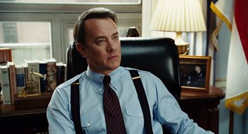 Movie still from “Charlie Wilson's War” (2007), directed by Mike Nichols – A man sitting in an office chair wearing suspenders; Close Up shot, Over the shoulder angle