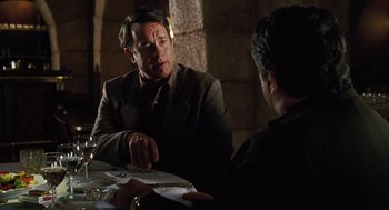 Movie still from “Charlie Wilson's War” (2007), directed by Mike Nichols – A man sitting at a table talking to another man; Medium shot, Over the shoulder angle