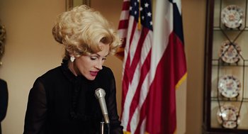 Movie still from “Charlie Wilson's War” (2007), directed by Mike Nichols – A woman in a black dress is holding a microphone; Close Up shot, Low angle