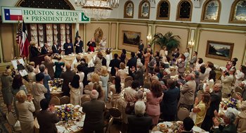 Movie still from “Charlie Wilson's War” (2007), directed by Mike Nichols – A group of people sitting at tables in a room; Wide shot, High angle