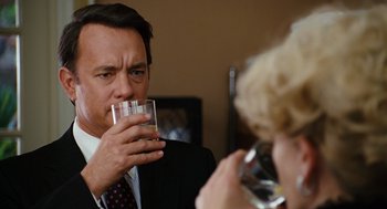Movie still from “Charlie Wilson's War” (2007), directed by Mike Nichols – A man drinking a glass of water while a woman takes a picture; Close Up shot, Over the shoulder angle