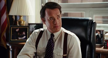Movie still from “Charlie Wilson's War” (2007), directed by Mike Nichols – A man in a white dress shirt and suspenders sitting in a chair; Close Up shot, Over the shoulder angle
