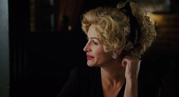 Movie still from “Charlie Wilson's War” (2007), directed by Mike Nichols – A woman with blonde curly hair wearing a black dress; Close Up shot, Over the shoulder angle