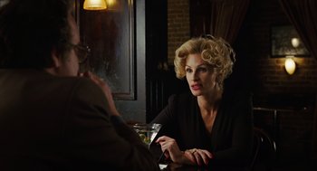 Movie still from “Charlie Wilson's War” (2007), directed by Mike Nichols – A woman sitting in front of a man at a table; Medium shot, Over the shoulder angle