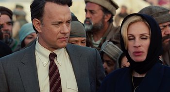 Movie still from “Charlie Wilson's War” (2007), directed by Mike Nichols – A man in a suit and tie standing next to a crowd of people; Close Up shot, Over the shoulder angle
