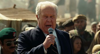 Movie still from “Charlie Wilson's War” (2007), directed by Mike Nichols – An older man is holding a microphone in his hand; Close Up shot, Low angle