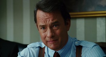 Movie still from “Charlie Wilson's War” (2007), directed by Mike Nichols – A man in a blue shirt and brown suspenders looks at the camera; Close Up shot, Over the shoulder angle