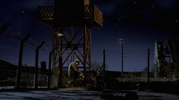 Movie still from “Chicken Run” (2000), directed by Peter Lord – A man sitting on a chair in the middle of a field at night; Wide shot, Low angle