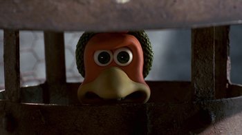 Movie still from “Chicken Run” (2000), directed by Peter Lord – An orange and green bird with big eyes; Extreme Close Up shot, High angle