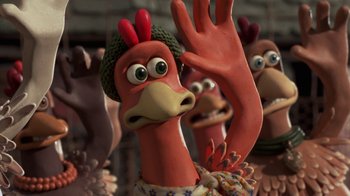 Movie still from “Chicken Run” (2000), directed by Peter Lord – A toy chicken with a hand raised; Close Up shot, High angle