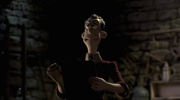 Movie still from “Chicken Run” (2000), directed by Peter Lord – A man holding an open book in front of a brick wall; Medium shot, Low angle